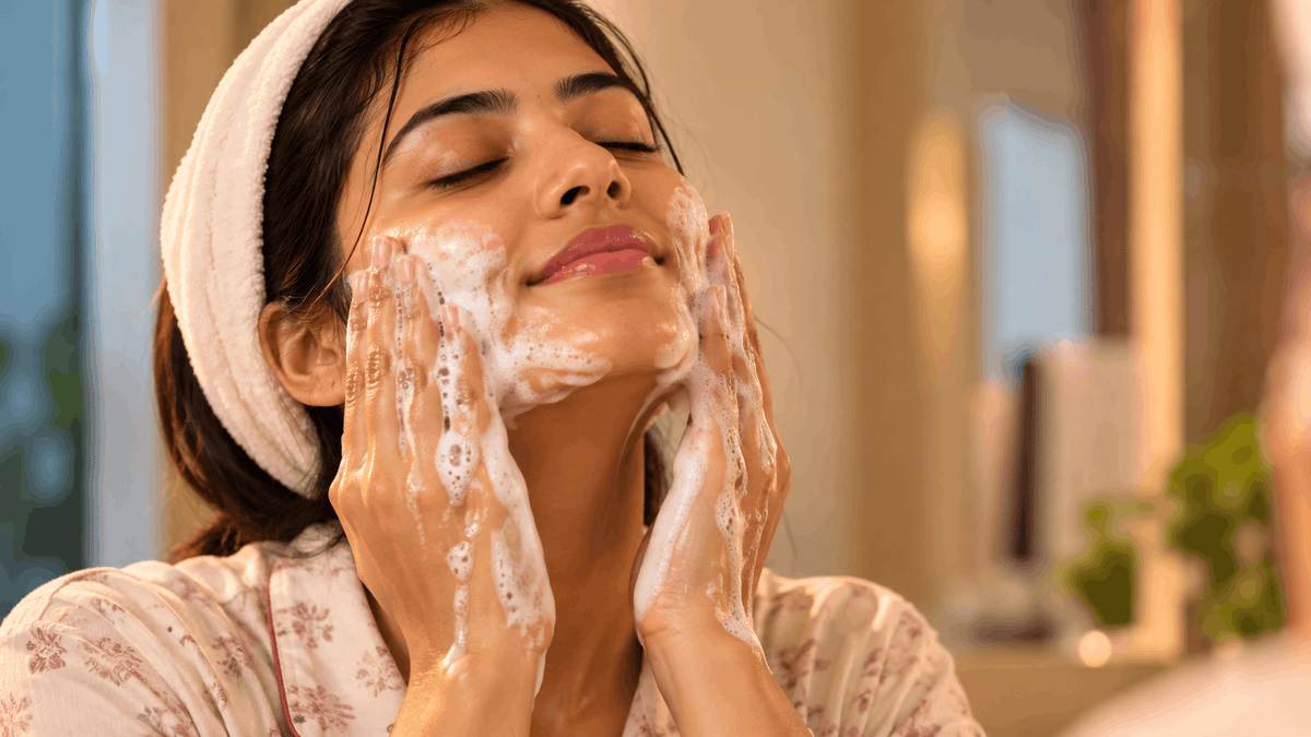 Woman washing her face with foamy cleanser in warm light