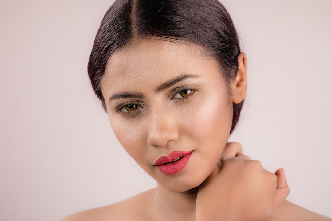 Young Indian woman with glowing, healthy skin and natural makeup against a soft neutral studio background