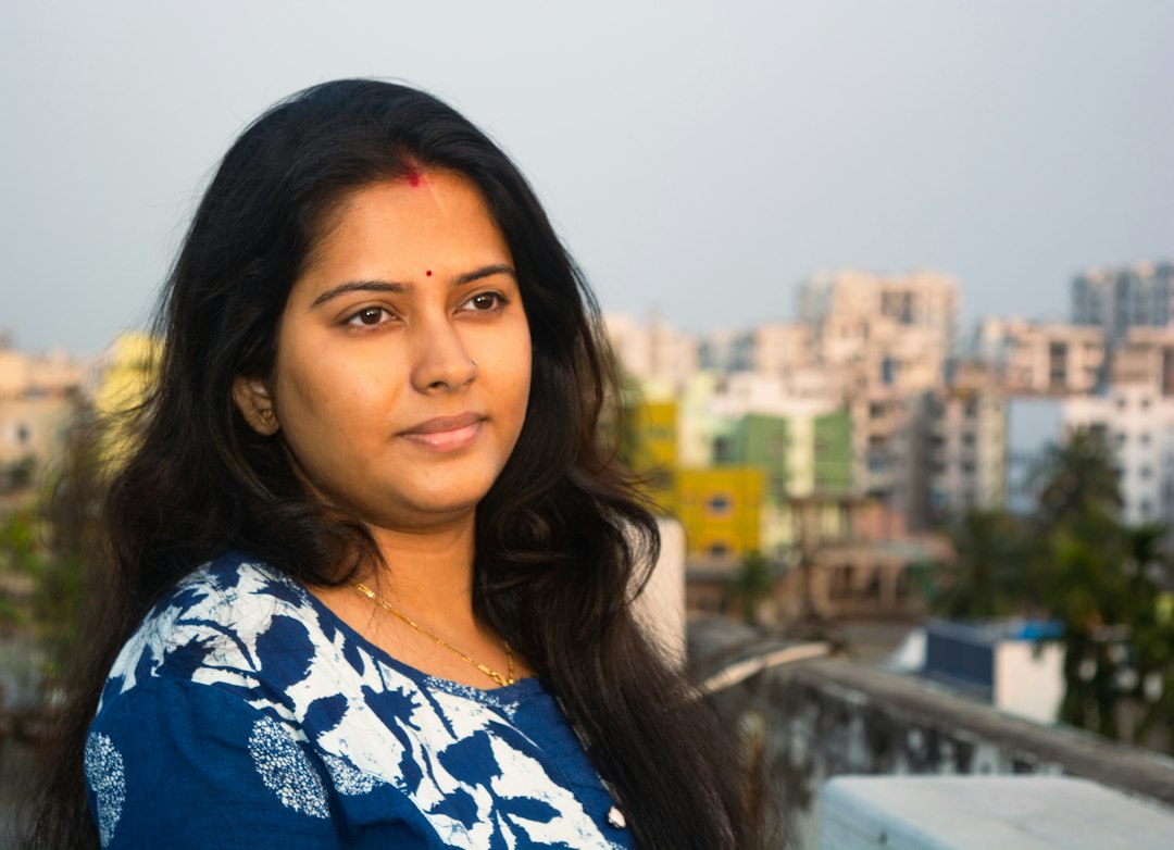 Young Indian woman standing on a rooftop with a hazy city skyline behind her