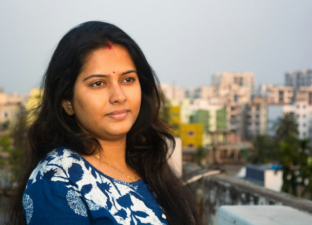Young Indian woman standing on a rooftop with a hazy city skyline behind her