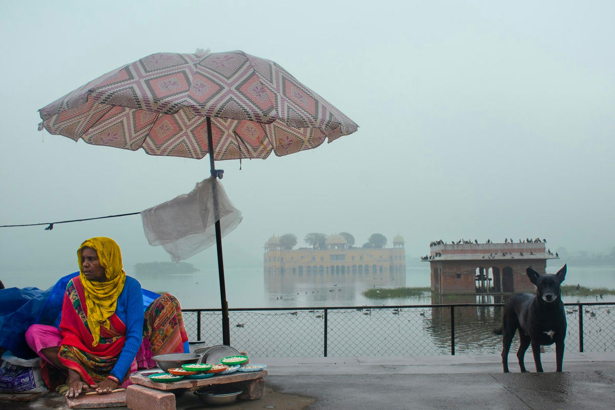 Hazy, humid monsoon-season scene with a woman sitting under an umbrella