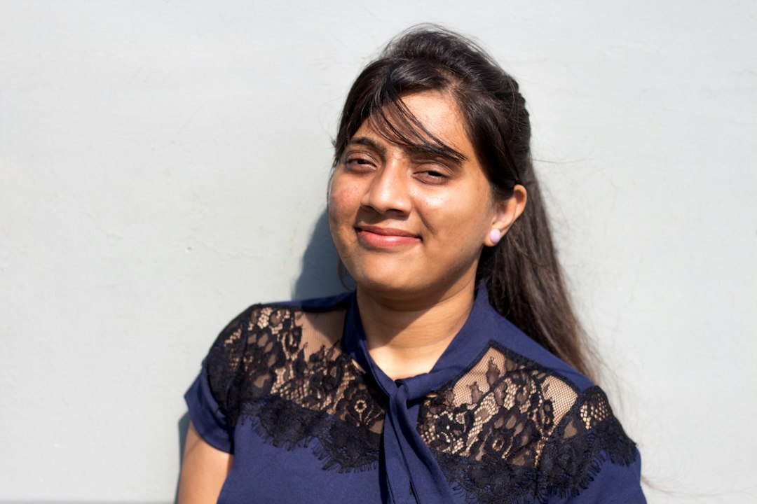 Smiling Indian woman with clear, glowing skin against a plain white studio background